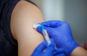 Injection given in arm by gloved hands.