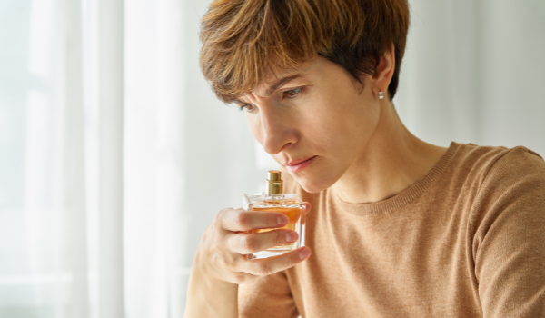 Woman standing in front of a building woman inhaling aroma from perfume bottle
